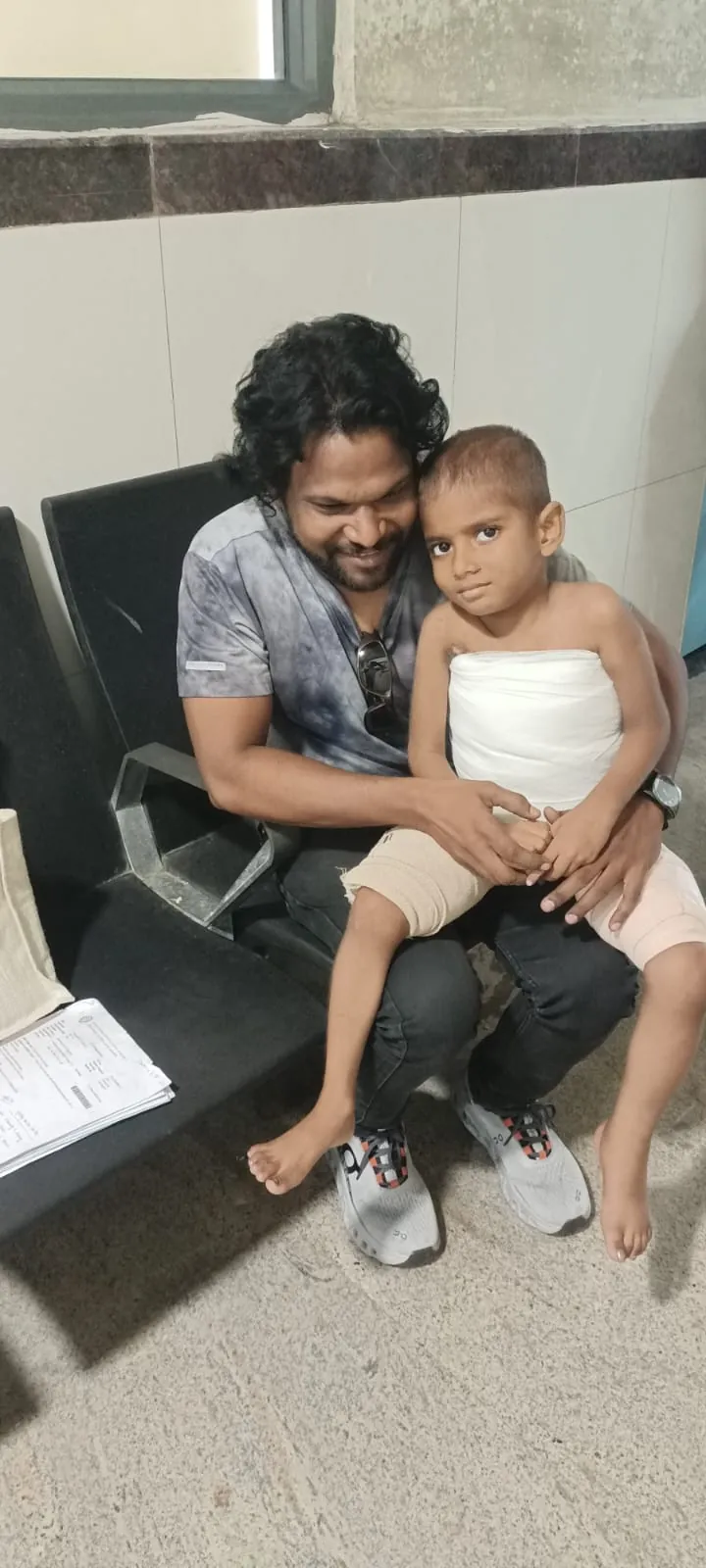 Gowtham sitting on a man's lap, both smiling